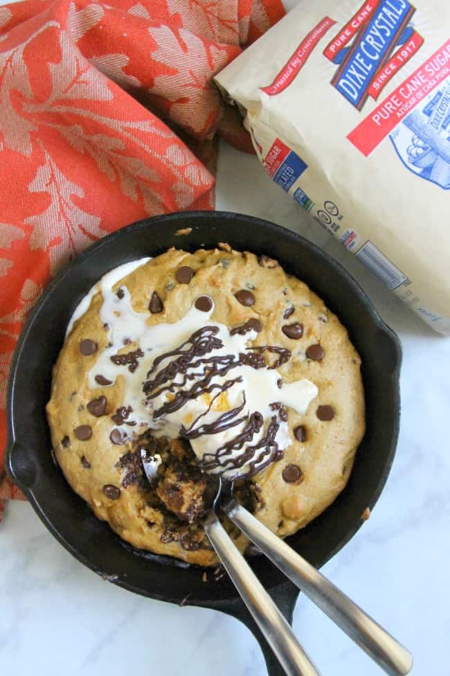 This Chocolate Chip Pumpkin Skillet Cookie is so much easier to make then a batch of cookies! It's super easy to make and perfect for fall! Chocolate Chip Pumpkin Skillet Cookie on white background in skillet with two spoons