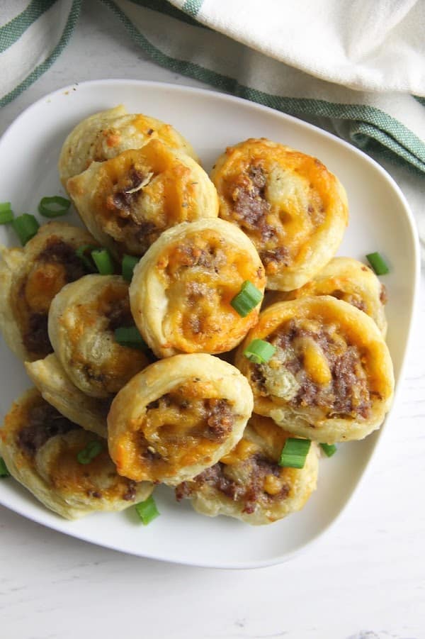 Puff Pastry Sausage Cheddar Pinwheels make a great game day snack. Filled with sausage and cheese they're great for dipping and so easy to make! | The Bitter Side of Sweet Puff Pastry Sausage Cheddar Pinwheels on white plate