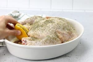 Oven Baked Whole Chicken with lemon pieces stuffed inside