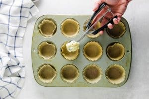 putting scoop of muffin mix into muffin pan