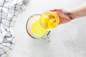 pouring eggs into glass measuring cup.