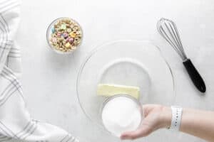 adding sugar into glass bowl with butter.