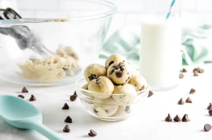 cookie dough bites in bowl with glass of milk.