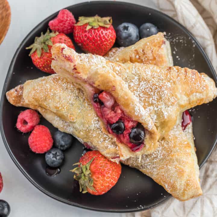 mixed berry turnover cut in half on plate.