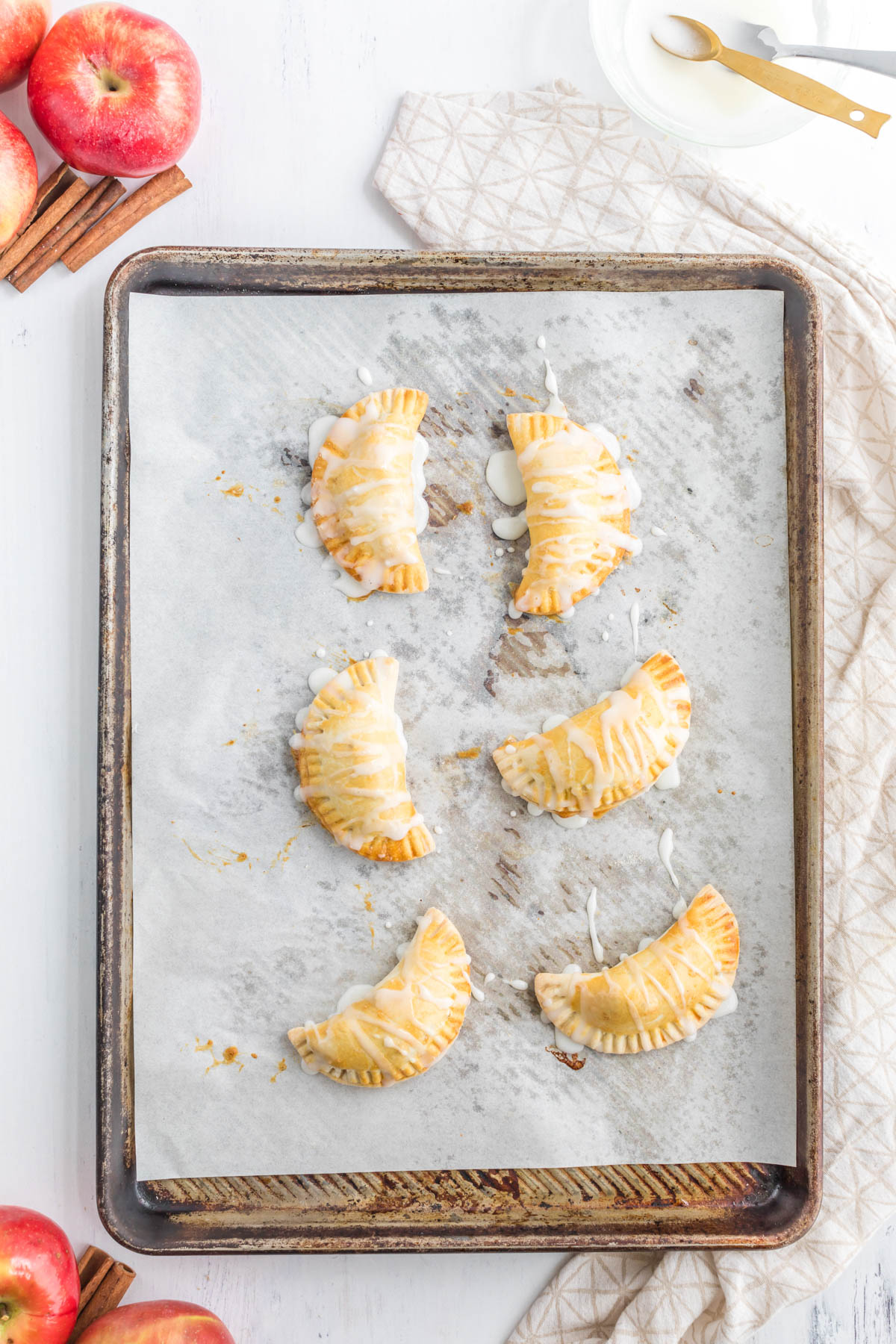 Homemade buttery pie crust filled with a delicious simple apple compote makes these Apple Pie Turnovers a new family favorite! Apple Pie Turnovers on tray with icing.