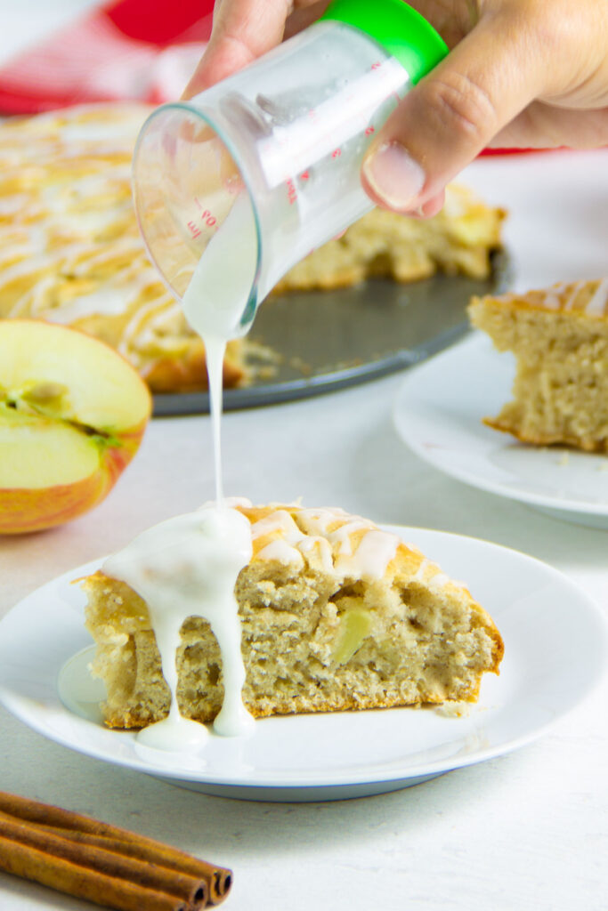 Easy Apple Cake! Made with just a few pantry staples and fresh apples! With a hint of cinnamon, this tasty dessert will become a favorite! drizzling icing on cake.