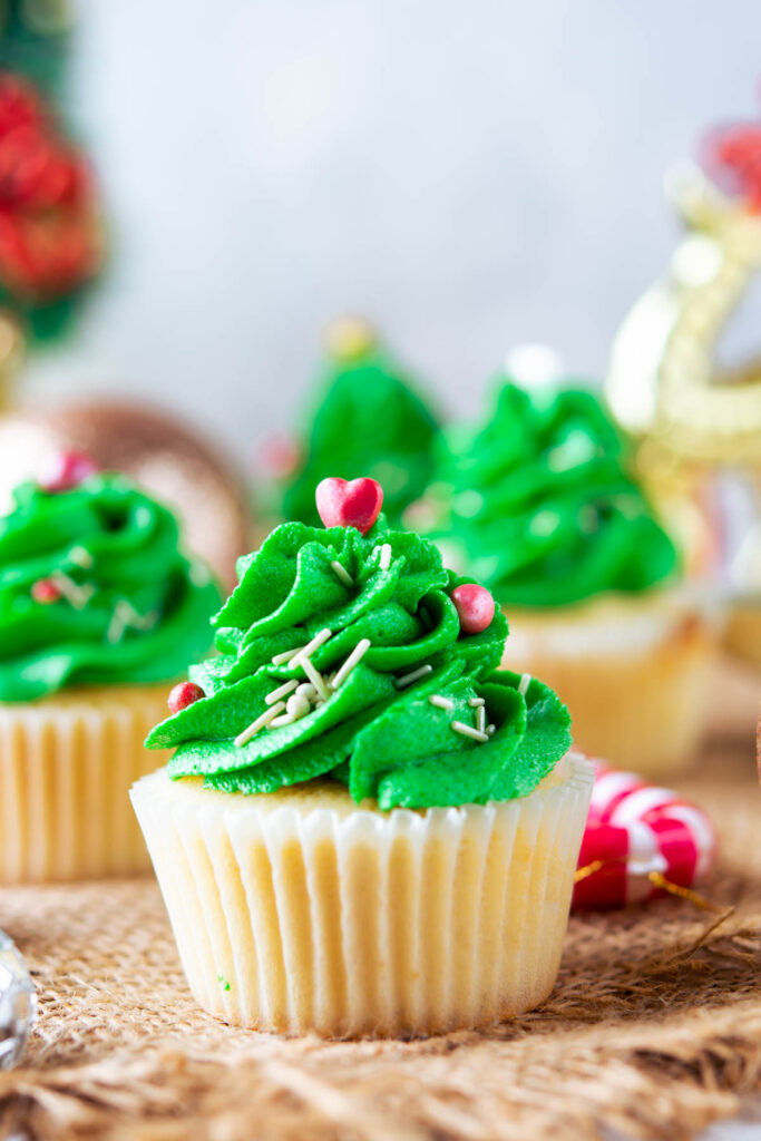 Homemade Christmas Tree Cupcakes that are moist and fluffy! Topped with a festive buttercream frosting! Christmas Tree Cupcakes on brown background.