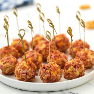 Mini Bacon Ranch Cheeseballs on white plate with toothpick.