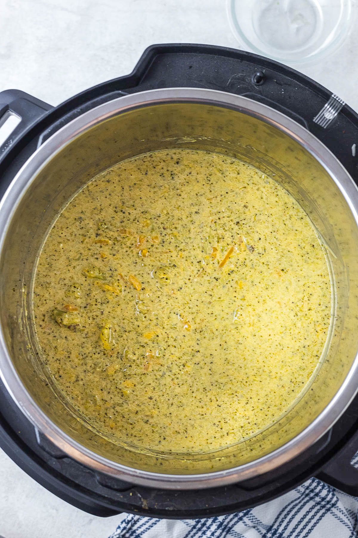 Instant Pot Broccoli Cheddar Soup in white bowl topped with cheese and crackers. soup cooked in instant pot.