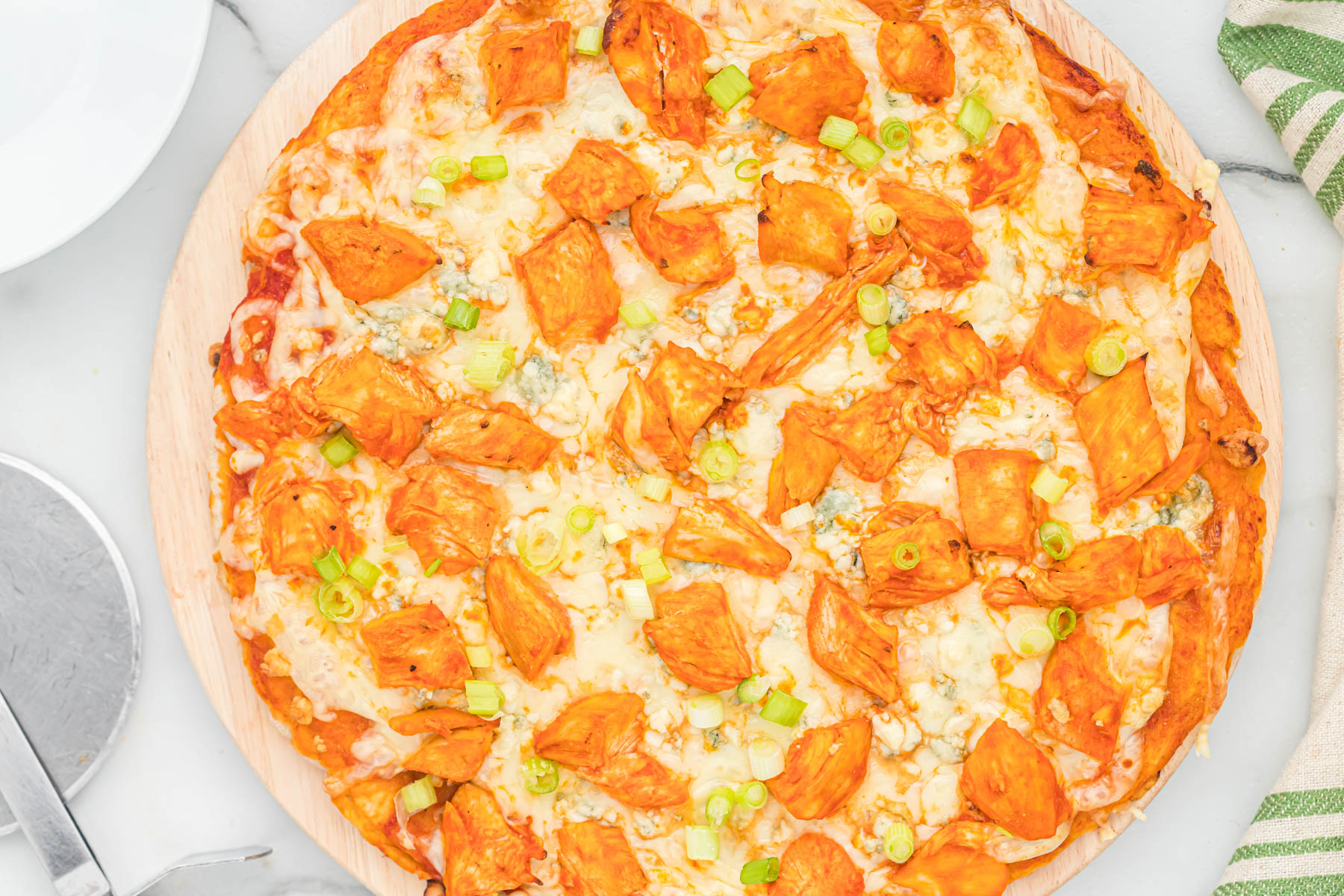 This easy buffalo chicken pizza starts with a homemade pizza dough, topped with chicken, blue cheese, and green onions. pizza topped with green onions.