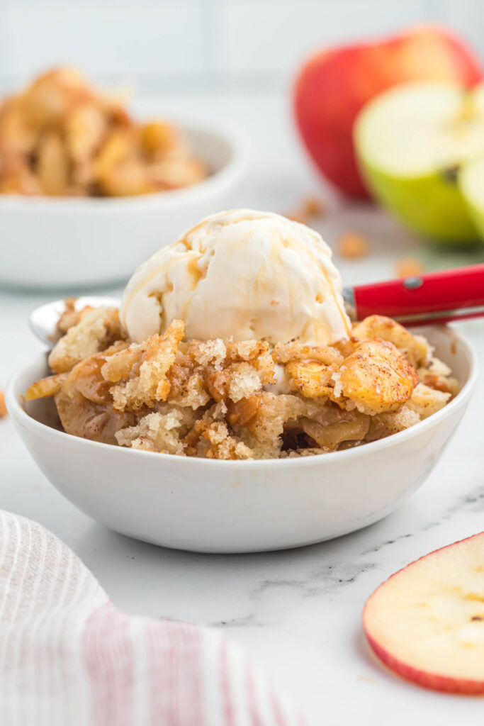 cobbler in bowl with red spoon topped with ice cream.