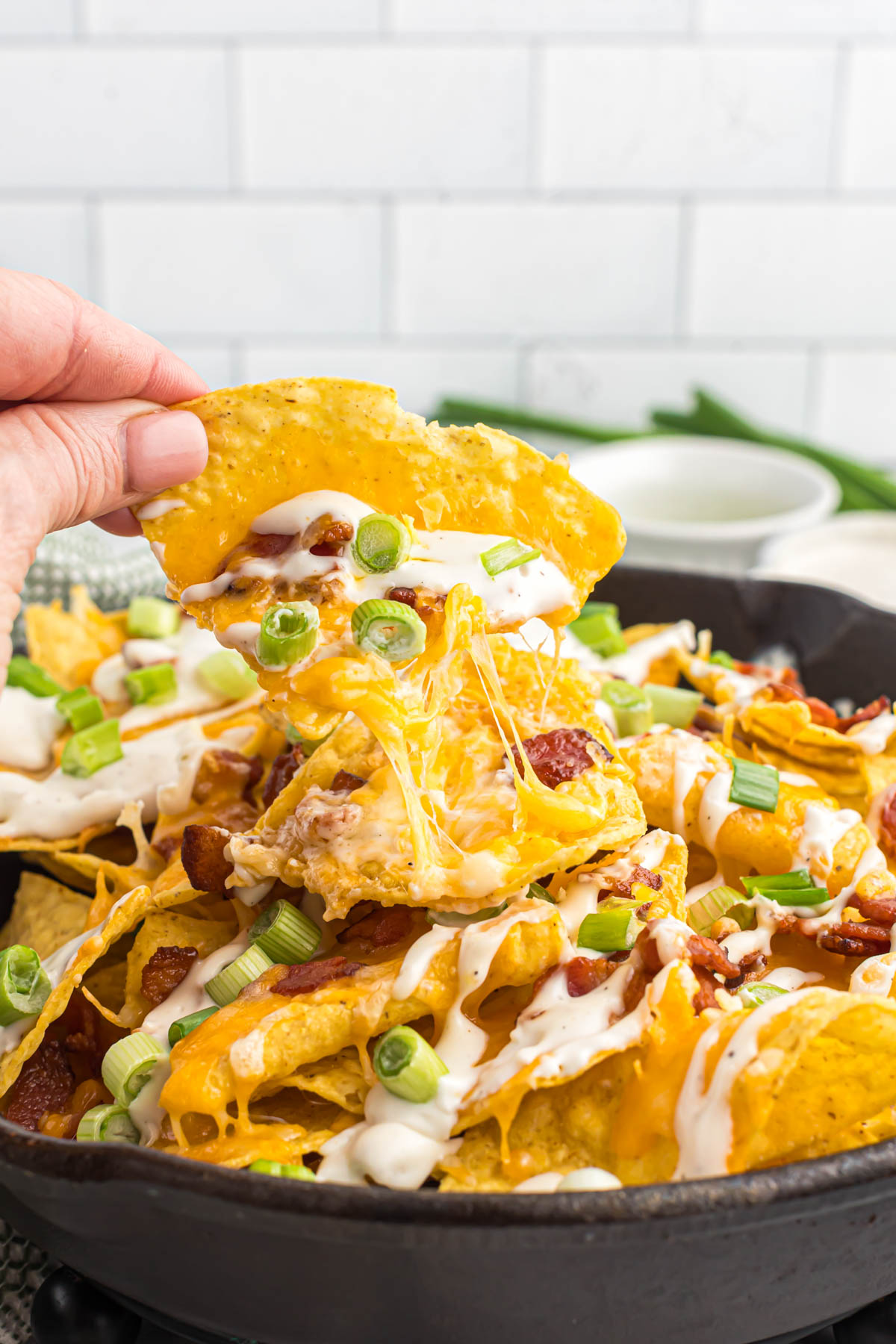 Whip up this quick and easy Bacon Ranch Skillet Nachos recipe in minutes. Crispy tortilla chips smothered in melty cheese, savory bacon, and creamy ranch dressing. cheesy bacon ranch skillet nachos