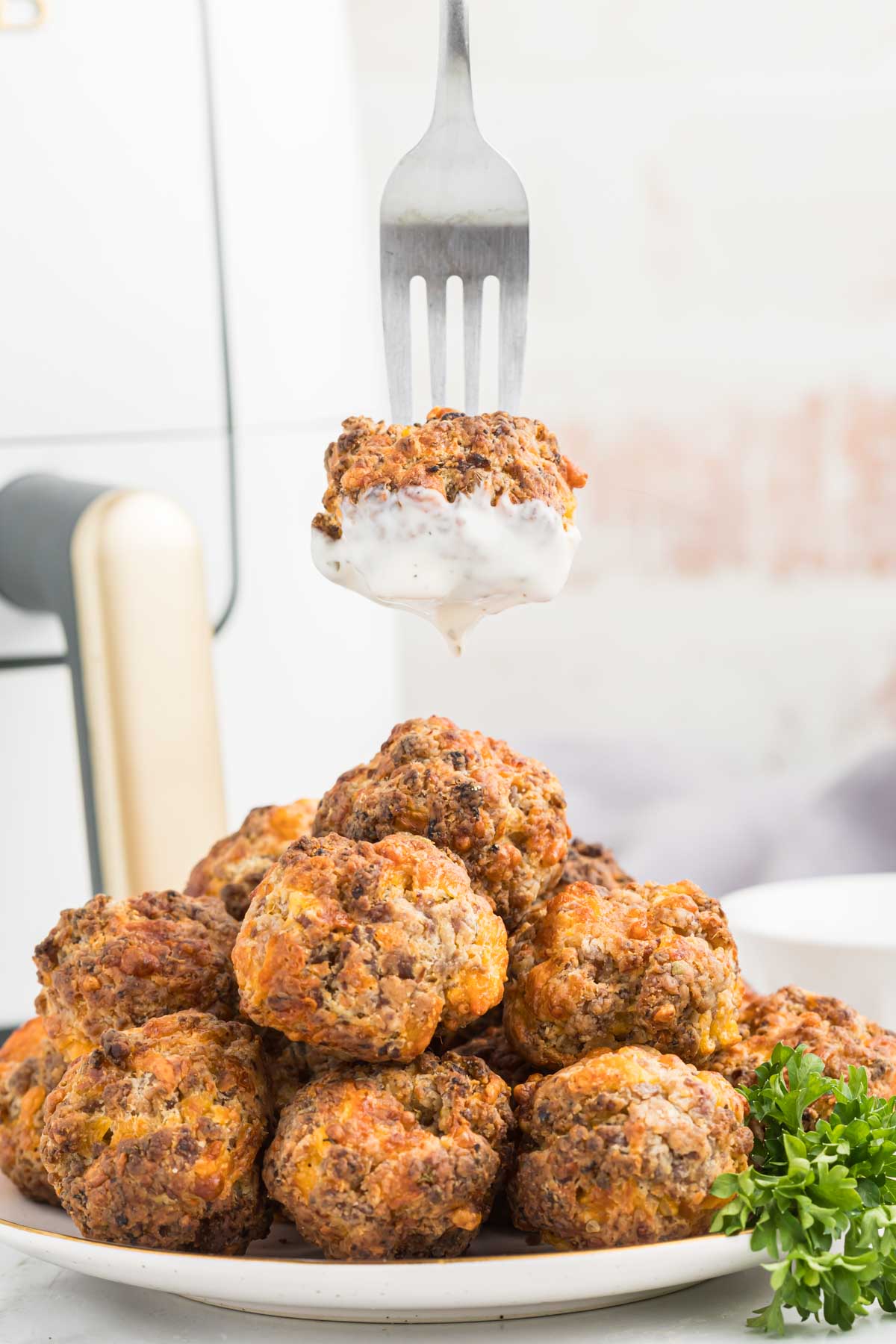 Air fryer sausage balls on fork with sauce.