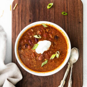 slow cooker chili in white bowl on wooden background.