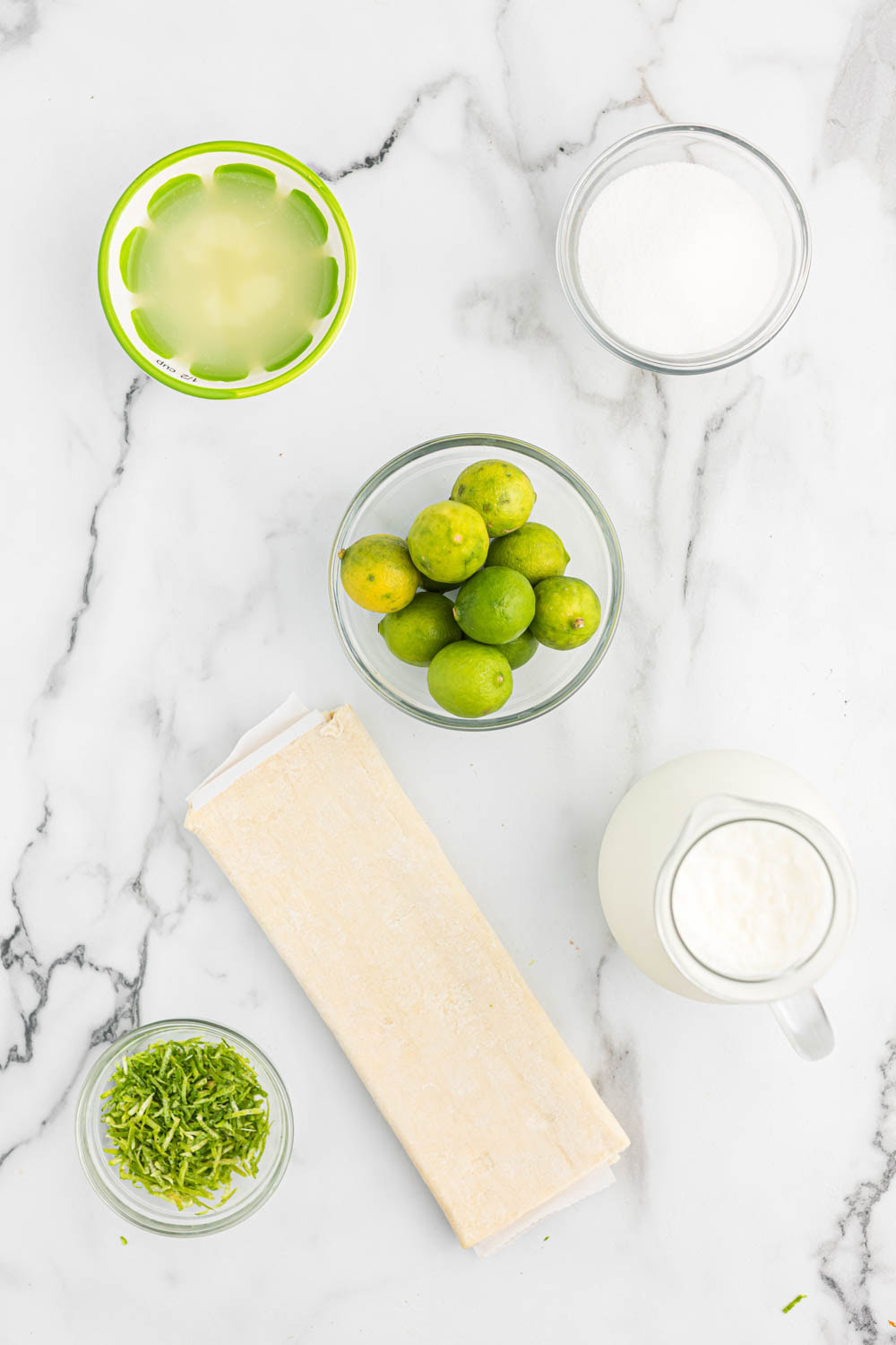 Ingredients for key lime tarts on marble background.
