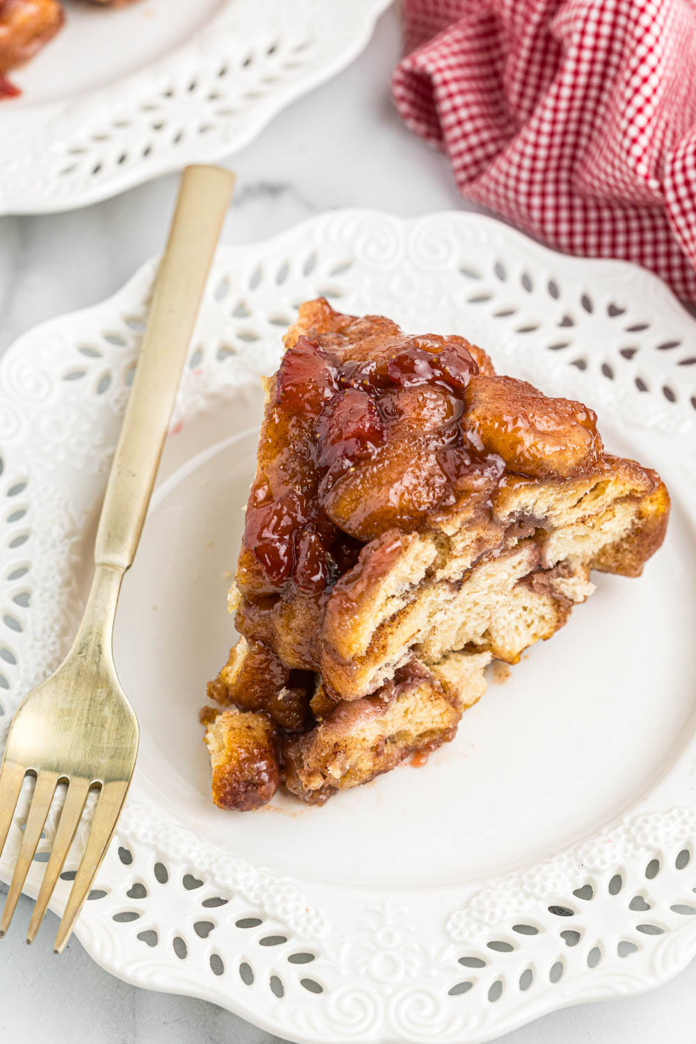 Slice of strawberry monkey bread on white plate with gold fork.