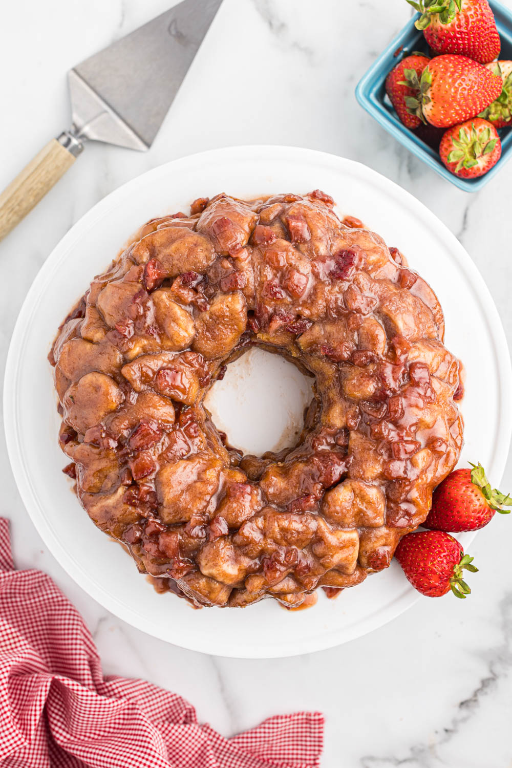 Overhead view of strawberry monkey bread on white plate with fresh strawberries.