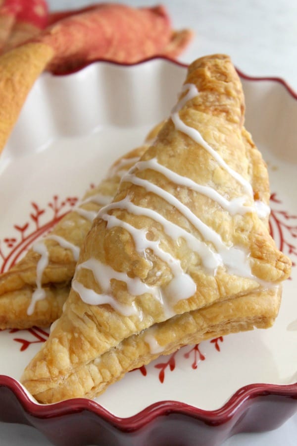 Pumpkin Pie Turnovers in red bowl with glaze drizzled over the top