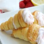 Lemon Raspberry Cream Horns stacked on white plate with raspberries and lemon