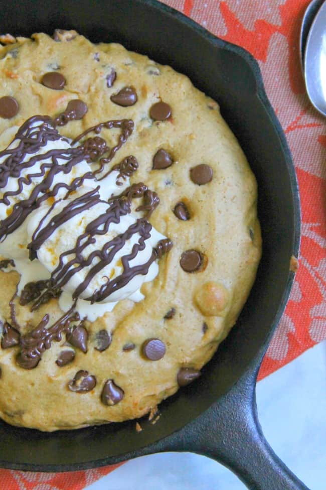 Chocolate Chip Pumpkin Skillet Cookie close up topped with ice cream and chocolate drizzle