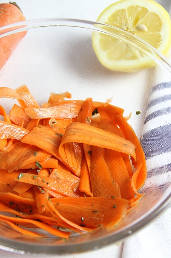 Lemon Carrot Salad in glass bowl with half lemon