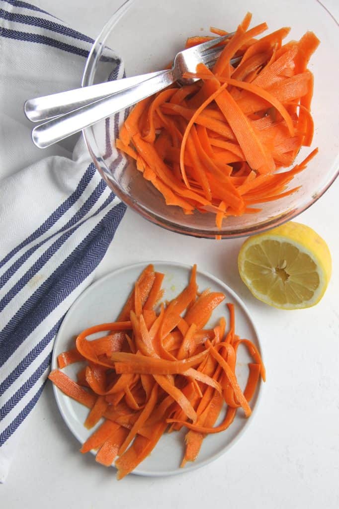 Lemon Carrot Salad in glass bowl with forks and on plate