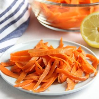 Lemon Carrot Salad on white plate with lemon