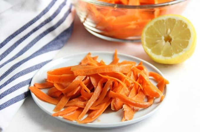 Lemon Carrot Salad on white plate with lemon