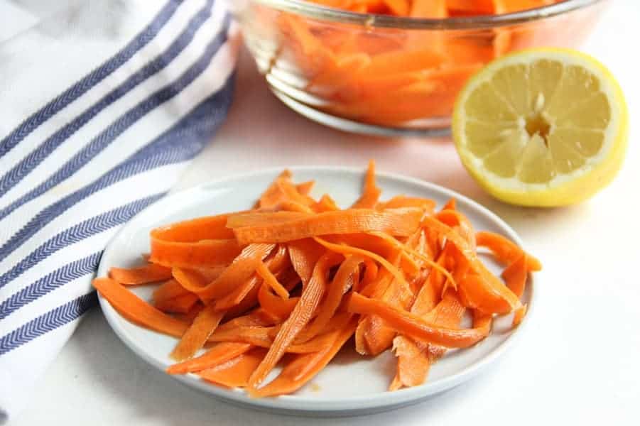 Lemon Carrot Salad on white plate with lemon