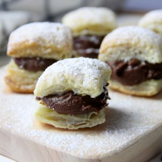 Miguelitos with Chocolate on cutting board topped with powdered sugar