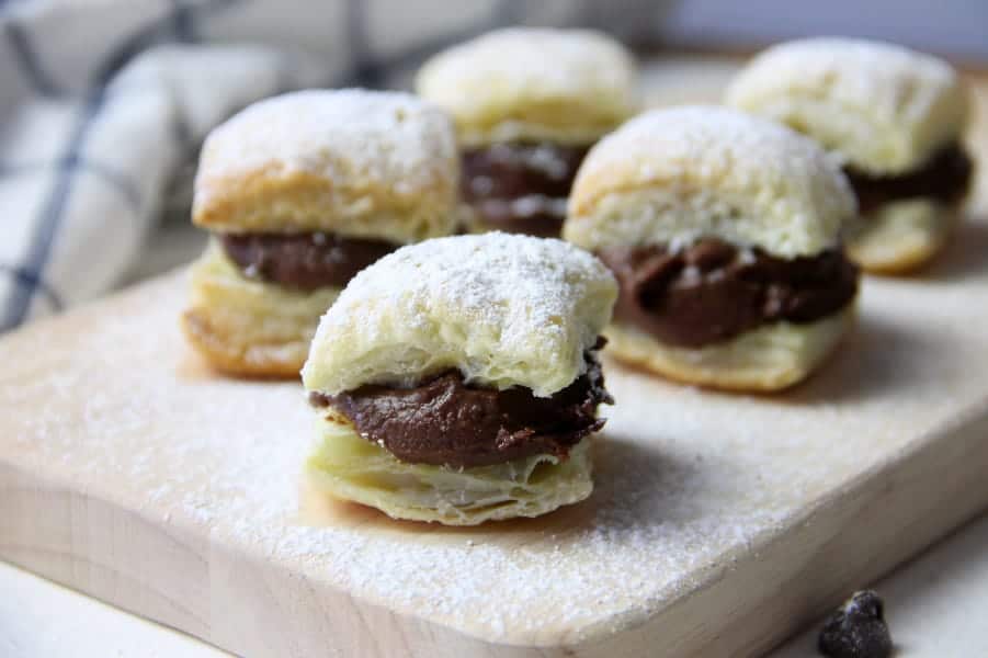 Miguelitos with Chocolate on cutting board topped with powdered sugar