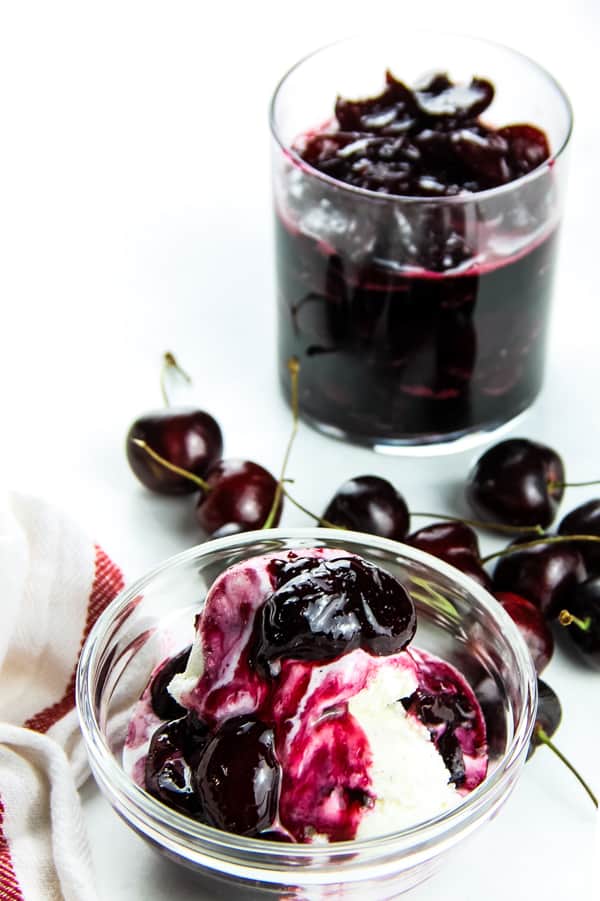 Easy Cherry Compote in glass bowl with ice cream and fresh cherries in background