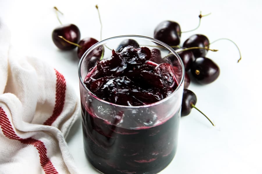 Easy Cherry Compote in glass cup with fresh cherries in background