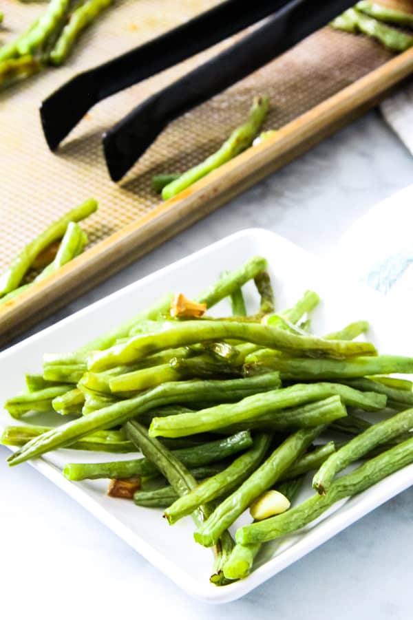 Sheet Pan Roasted Green Beans on white plate with sheet pan in background