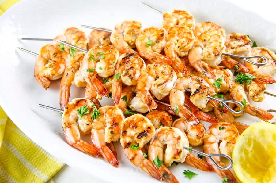 Grilled Lemon Shrimp Skewers on white plate with yellow towel topped with parsley