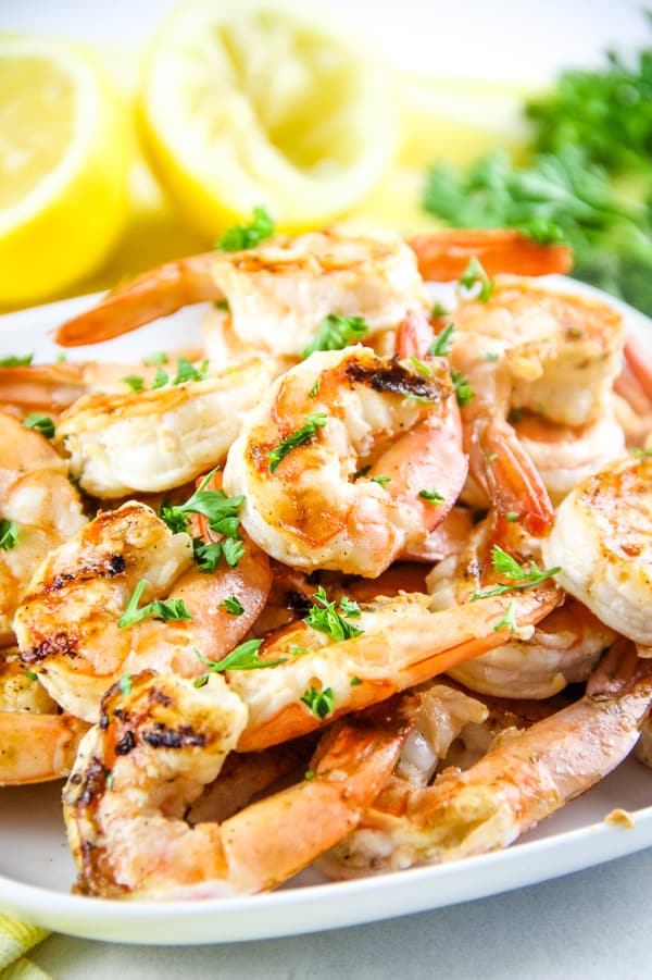 Grilled Lemon Shrimp Skewers with shrimp stacked on a white plate