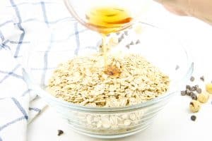 Chocolate Hazelnut Granola maple syrup being poured in bowl