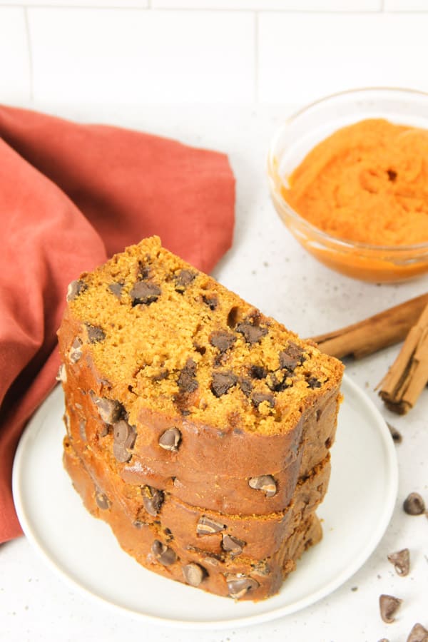 Chocolate Chip Pumpkin Bread on white plate with pumpkin in a glass bowl