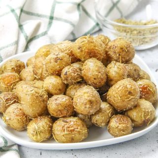 Roasted Rosemary Potatoes on white plate with spoon