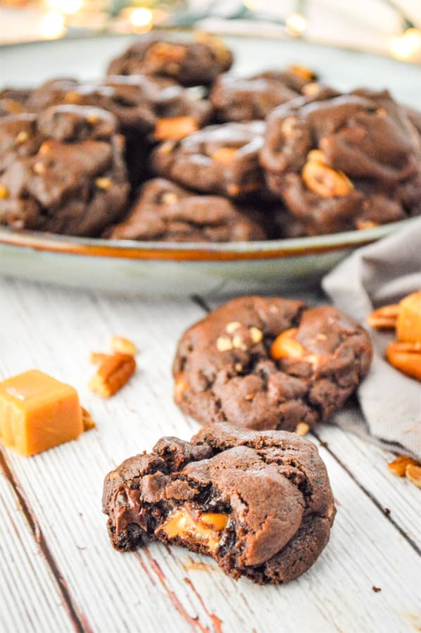 Chocolate Turtle Cookies with bite out of cookie on white background