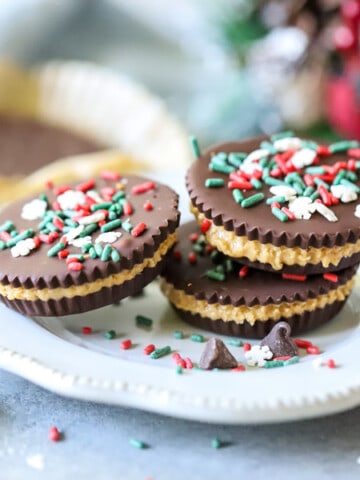 Homemade Peanut Butter Cups stacked on white plate with holiday sprinkles