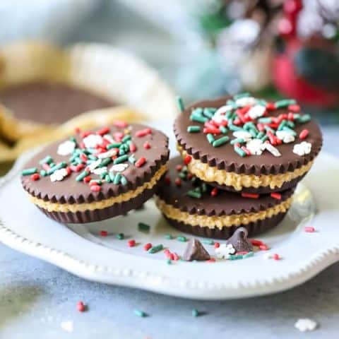 Homemade Peanut Butter Cups stacked on white plate with holiday sprinkles