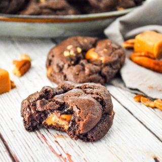 Chocolate Turtle Cookies on white background with caramels and pecans