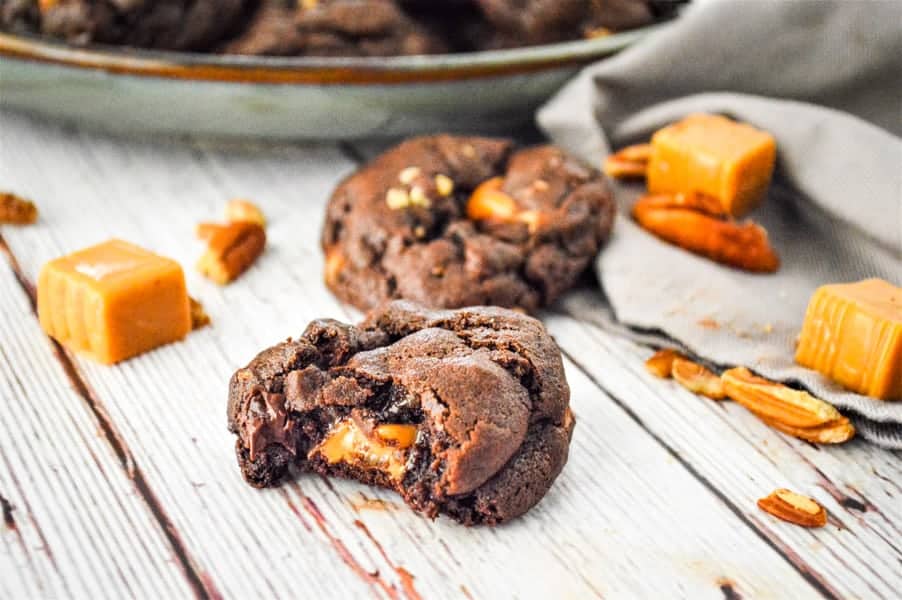 Chocolate Turtle Cookies on white background with caramels and pecans
