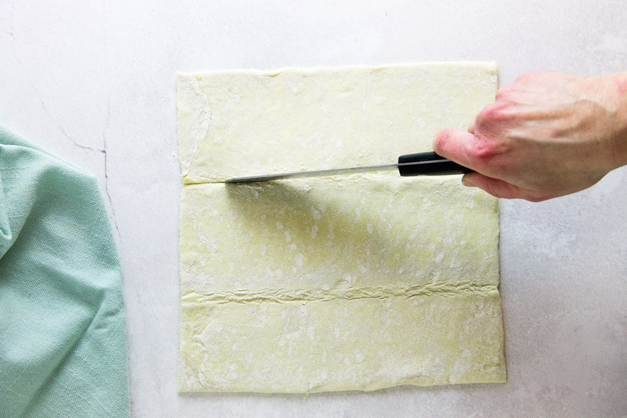 using knife to cut strips in puff pastry dough.