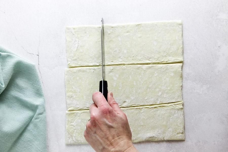 using knife to cut squares in puff pastry dough.
