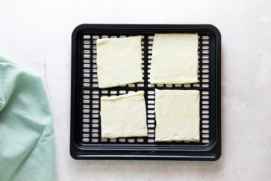 uncooked beignets on air fryer tray.