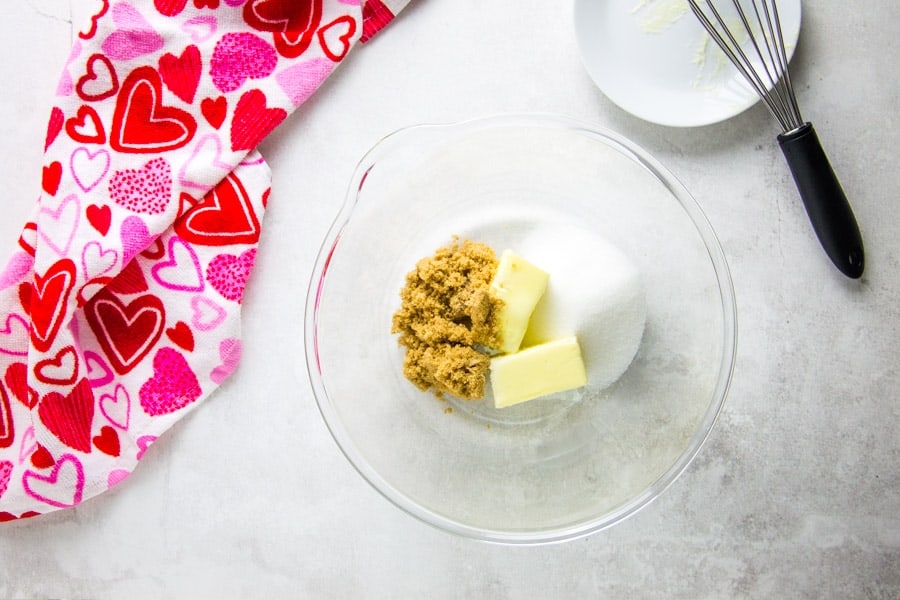 uncooked cookie ingredients in glass bowl with butter and sugar