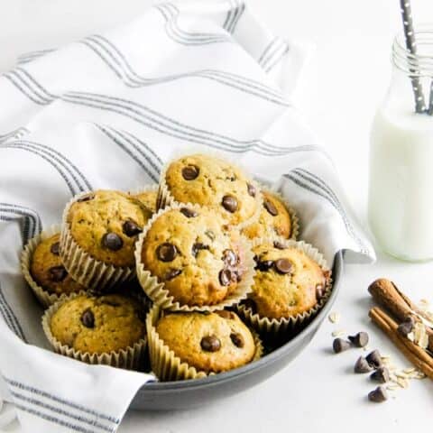 Muffins in bowl with glass of milk.