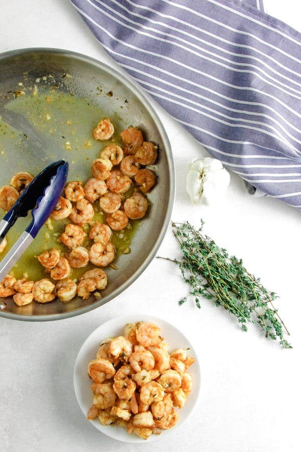 Spicy Garlic Thyme Shrimp in pan and on white plate.